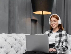 Pessoa jovem iniciando carreira no home office, trabalhando remotamente em casa com notebook e fones de ouvido.